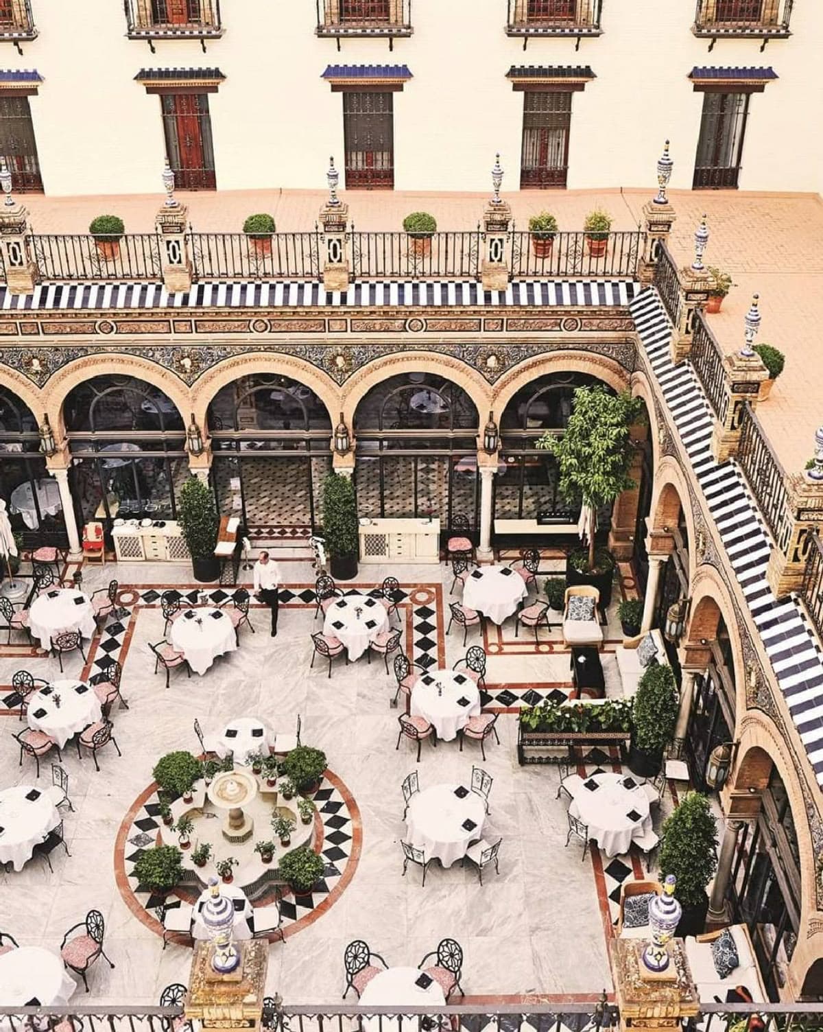 Overhead view of a tiled courtyard dining room with round tables set for service